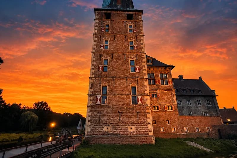 Schloss Raesfeld im Abendrot, davor die Brücke zum Restaurant Mahl & Meute