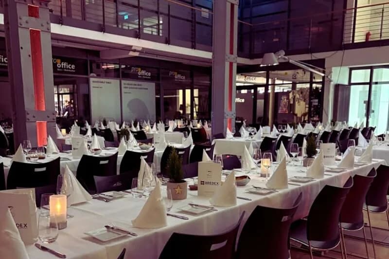 Lange festlich gedeckte Tafel in der Backsteinhalle des Zucker in Braunschweig, im Hintergrund hohe Industriefenster