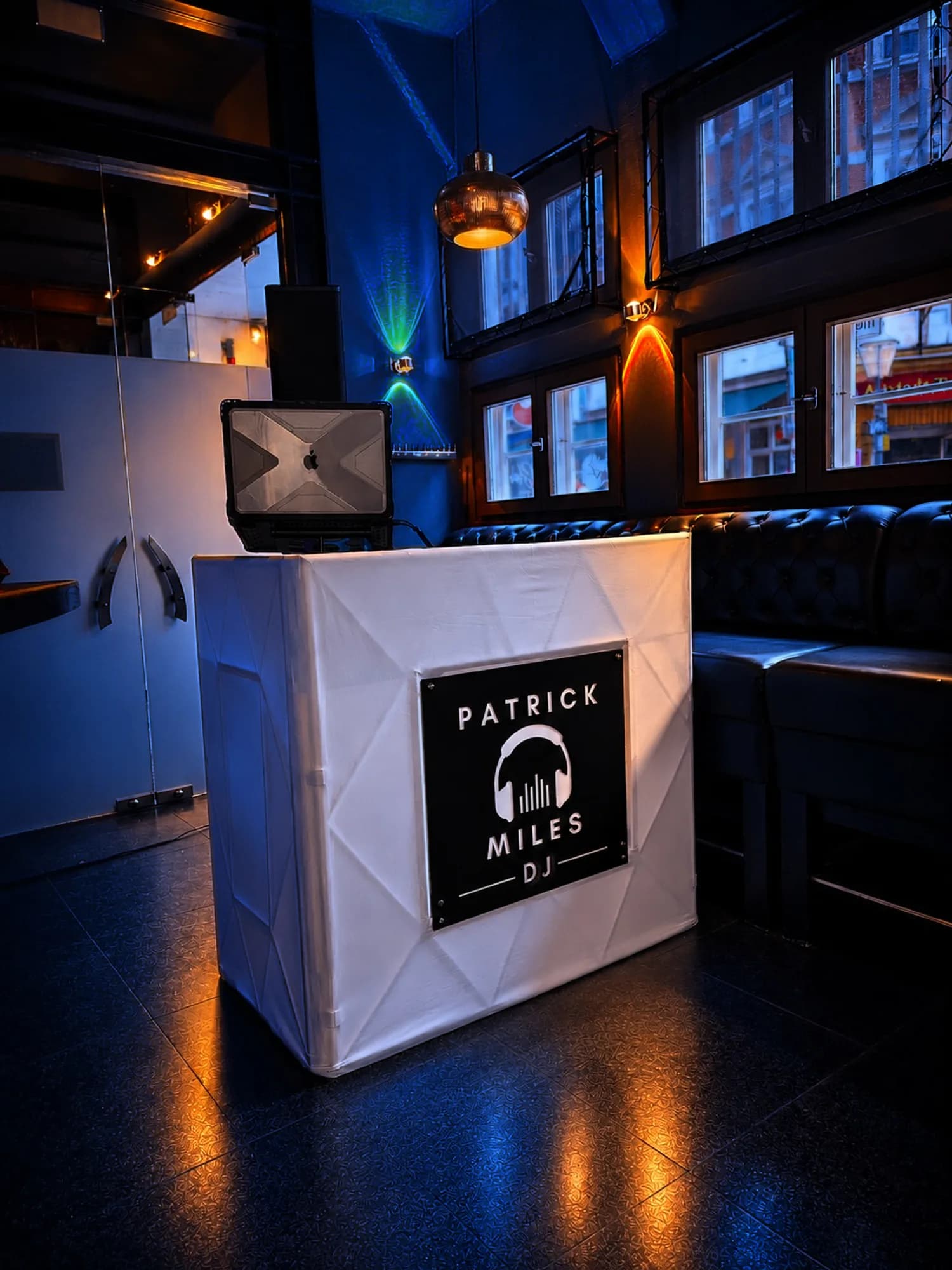 Beleuchtetes DJ-Pult mit dem Logo von Patrick Miles in einer Bar, blaues und warmes Licht